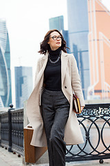 Image showing beautiful businesswoman in a light coat, with a wooden case and 