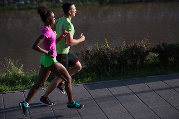 Image showing young smiling multiethnic couple jogging in the city