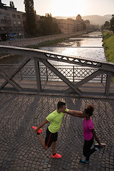 Image showing jogging couple warming up and stretching in the city