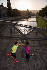 Image showing jogging couple warming up and stretching in the city