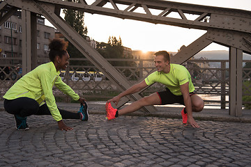 Image showing jogging couple warming up and stretching in the city