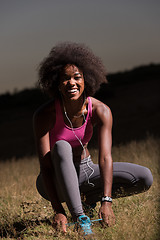 Image showing black woman runner tightening shoe lace