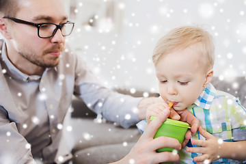 Image showing father and son drinking from cup at home