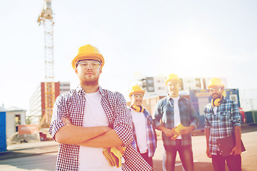 Image showing group of smiling builders in hardhats outdoors