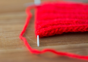 Image showing hand-knitted item with knitting needles on wood