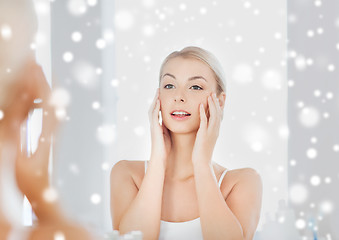 Image showing happy young woman looking to mirror at bathroom