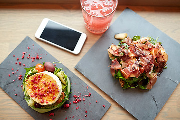 Image showing goat cheese and ham salads with smartphone at cafe