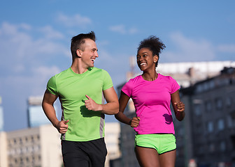 Image showing young smiling multiethnic couple jogging in the city