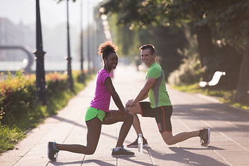 Image showing jogging couple warming up and stretching in the city