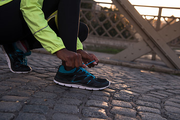 Image showing African american woman runner tightening shoe lace