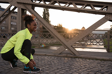 Image showing African american woman runner tightening shoe lace