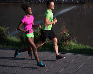 Image showing young smiling multiethnic couple jogging in the city