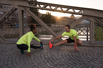 Image showing jogging couple warming up and stretching in the city