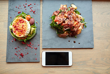 Image showing goat cheese and ham salads with smartphone at cafe