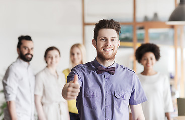 Image showing happy man showing thumbs up over team in office