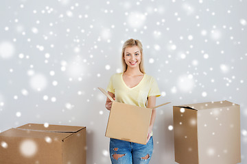 Image showing smiling young woman with cardboard box at home