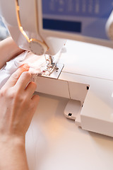 Image showing Seamstress sewing white cloth close-up