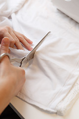 Image showing Woman cuts cloth with scissors