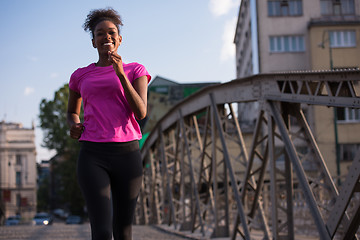 Image showing african american woman running across the bridge