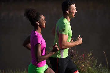 Image showing young smiling multiethnic couple jogging in the city