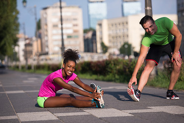 Image showing jogging couple warming up and stretching in the city