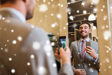 Image showing man in suit taking mirror selfie at clothing store