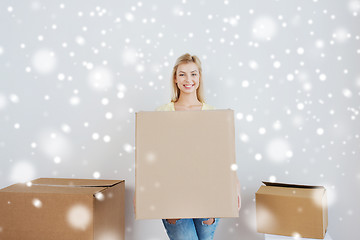 Image showing smiling young woman with cardboard box at home