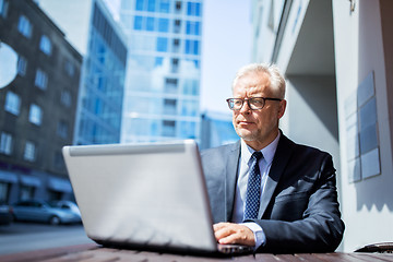 Image showing senior businessman with laptop at city street cafe