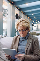 Image showing Mid age woman with tablet sitting cafe
