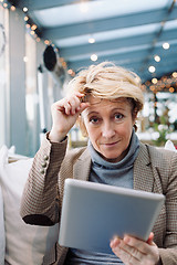 Image showing Mid age woman with tablet sitting cafe