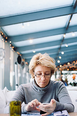 Image showing Mid age woman with cell phone sitting cafe