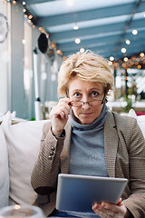 Image showing Mid age woman with tablet sitting cafe