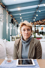 Image showing Mid age woman with tablet sitting cafe