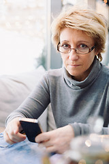 Image showing Mid age woman with cell phone sitting cafe