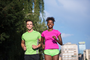 Image showing young smiling multiethnic couple jogging in the city