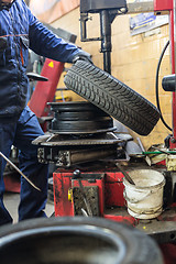 Image showing Professional auto mechanic replacing tire on wheel in car repair service.