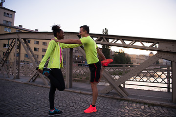 Image showing jogging couple warming up and stretching in the city