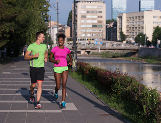 Image showing young smiling multiethnic couple jogging in the city