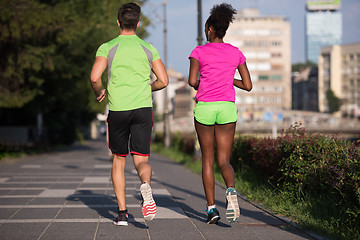 Image showing young smiling multiethnic couple jogging in the city