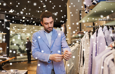 Image showing happy young man trying jacket on in clothing store