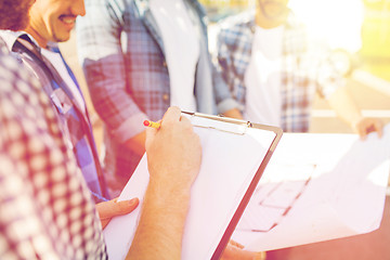 Image showing close up of builders with clipboard and blueprint