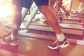 Image showing close up of men legs walking on treadmills in gym
