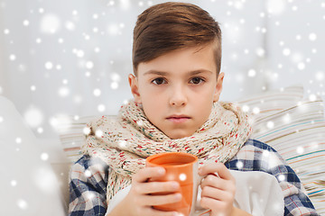 Image showing ill boy with flu in scarf drinking tea at home