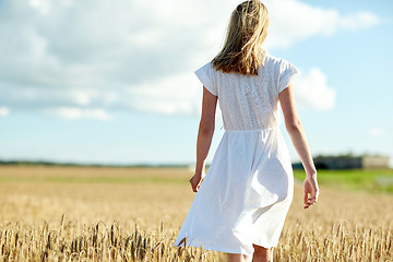 Image showing young woman in white dress walking along on field