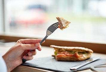 Image showing woman eating salmon panini sandwich at restaurant