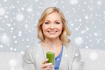 Image showing happy woman drinking green juice or shake at home