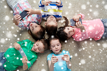 Image showing happy children with smartphones lying on floor