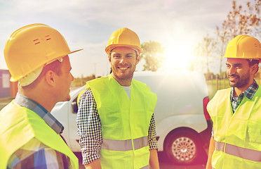 Image showing happy male builders in high visible vests outdoors