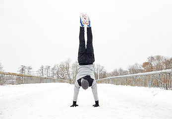 Image showing young man doing handstand in winter