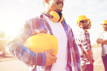 Image showing close up of builder holding hardhat at building